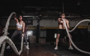 man and woman using battle ropes