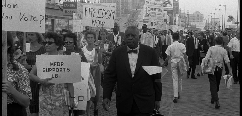 African American and white Mississippi Freedom Democratic Party supporters holding signs reading "Freedom now" and "MFDP supports LBJ" while marching on the boardwalk at the 1964 Democratic National Convention, Atlantic City, New Jersey