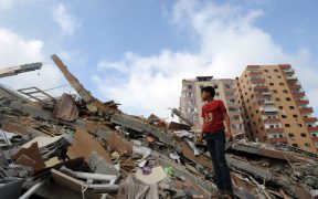 Palestinians collect their belongings from under the rubble of a residential tower, which witnesses said was destroyed in an Israeli air strike in Gaza City on August 24, 2014.