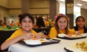 Three children enjoy lunch freshly prepared and served on-site by a food service management company at the Inter Metro Summer Recreation Program in San Juan, Puerto Rico.