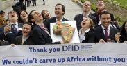 WDM campaigners dressed as business people from Monsanto, Diageo, SABMiller and Unilever deliver a cake to the Department for International Development to thank the UK government for its support to allow them to carve up Africa.