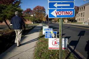A voter walks past candidate signs on election day 2014.