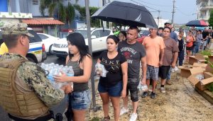 A Coast Guard member deployed to Borinquen, Puerto Rico in support of Hurricane Maria relief efforts delivers a case of water to a resident of Moca, Puerto Rico, Oct. 9, 2017.