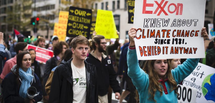 Climate activists demonstrate in Washington, D.C. in 2015. One displays a sign admonishing ExxonMobil for its complicity in furthering the climate apocalypse.