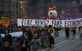 Protesters hold sign saying "fake news? fake economy! during January 2017 protest of Donald Trump inauguration.