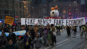 Protesters hold sign saying "fake news? fake economy! during January 2017 protest of Donald Trump inauguration.