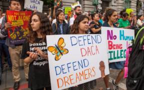 Protesters hold various signs and banners at a DACA rally in San Francisco.