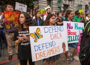 Protesters hold various signs and banners at a DACA rally in San Francisco.