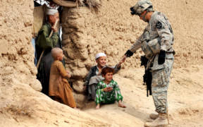 U.S. Army Sgt. Jose Gonzalez gives snacks to Afghan children during a patrol in Dagyan village in Helmand province, Afghanistan, Feb. 21, 2010. Gonzalez is assigned to Company C, 4th Battalion, 23rd Infantry Regiment. U.S. Air Force photo by Staff Sgt. Christine Jones