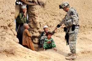 U.S. Army Sgt. Jose Gonzalez gives snacks to Afghan children during a patrol in Dagyan village in Helmand province, Afghanistan, Feb. 21, 2010. Gonzalez is assigned to Company C, 4th Battalion, 23rd Infantry Regiment. U.S. Air Force photo by Staff Sgt. Christine Jones