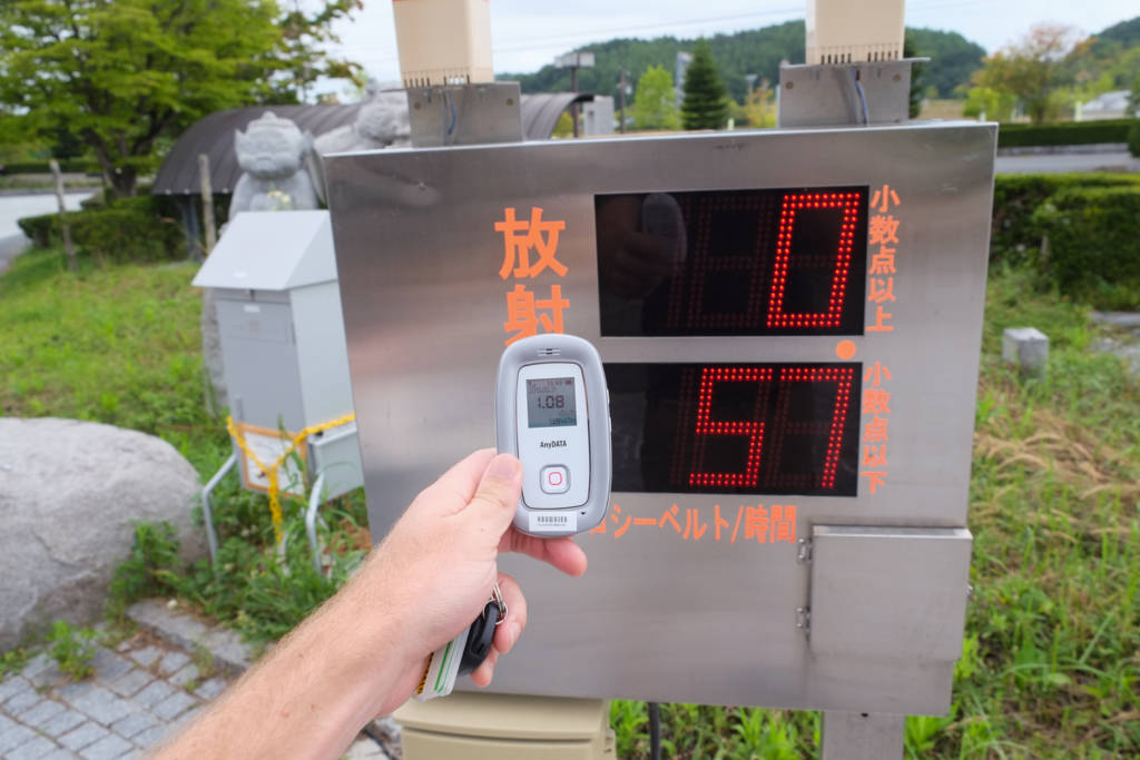 Author comparing the readings of handheld geiger counter with official monitoring post in Iitate, Fukushima Prefecture. Date: Aug. 2013. (Photo: Miguel Quintana)