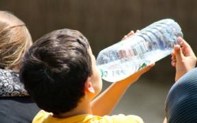 child drinking from a plastic water bottle
