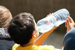 child drinking from a plastic water bottle