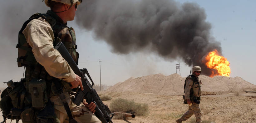 U.S. Army Sgt. Mark Phiffer stands guard duty near a burning oil well in the Rumaylah Oil Fields in Southern Iraq.